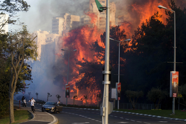 People run as wildfires rages in Haifa, Israel, on Thursday (AP photo)